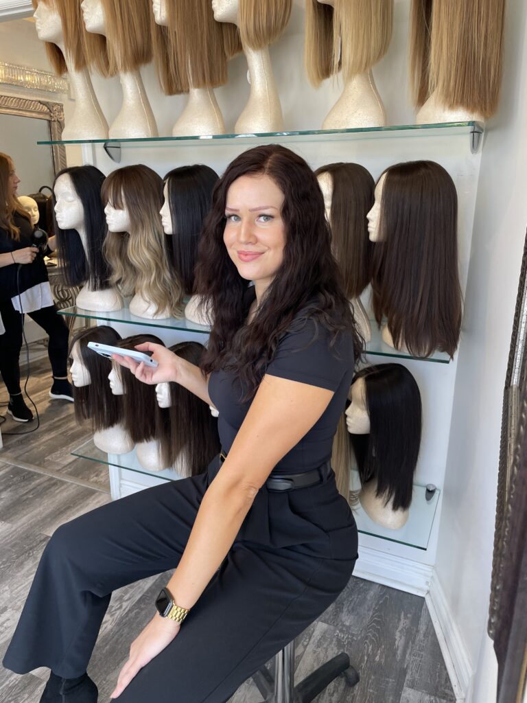 Woman sitting in front of wigs