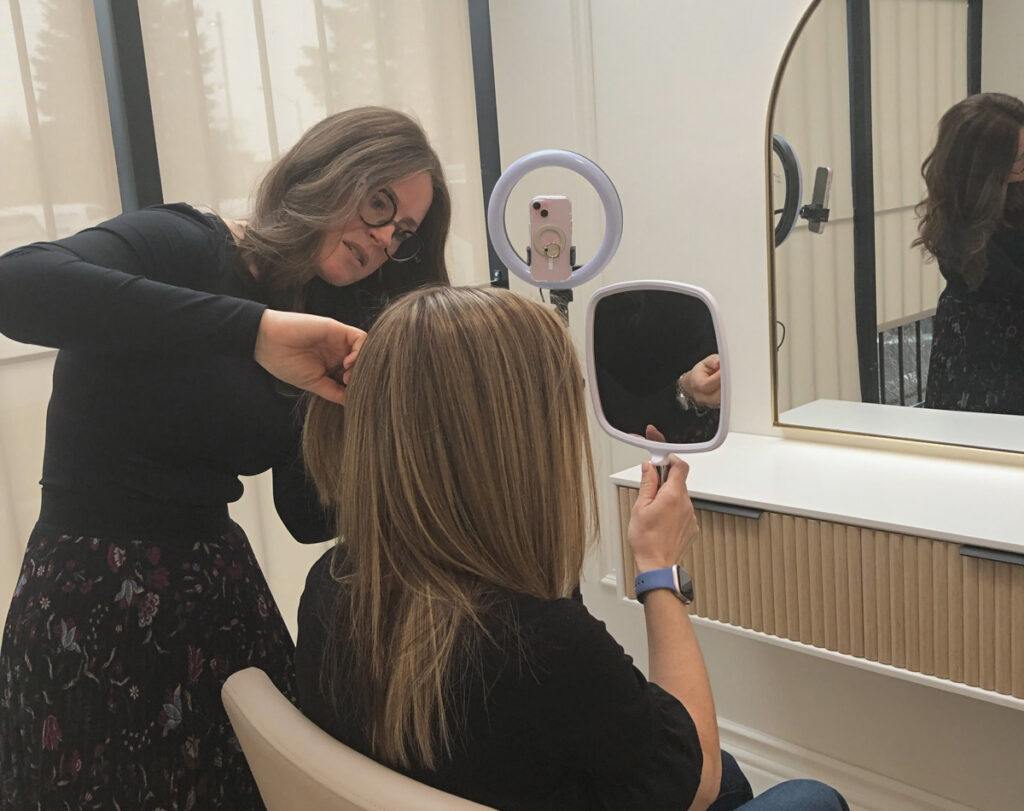 Wig consultant fitting wig on woman in chair